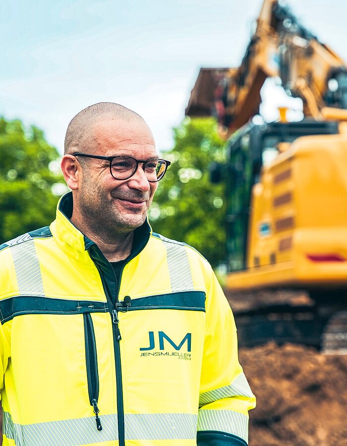 Mitarbeiter vor einem Bagger auf einer Baustelle