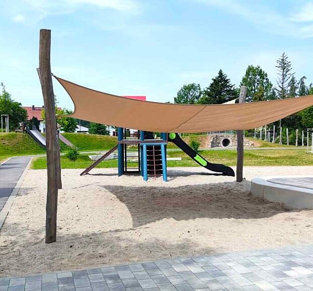 Gestaltete Freianlage mit Spielplatz und Sonnensegel