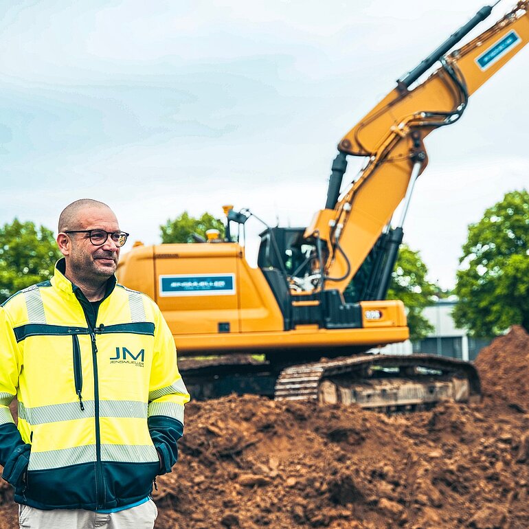 Mitarbeiter auf einer Baustelle vor einem Kettenbagger