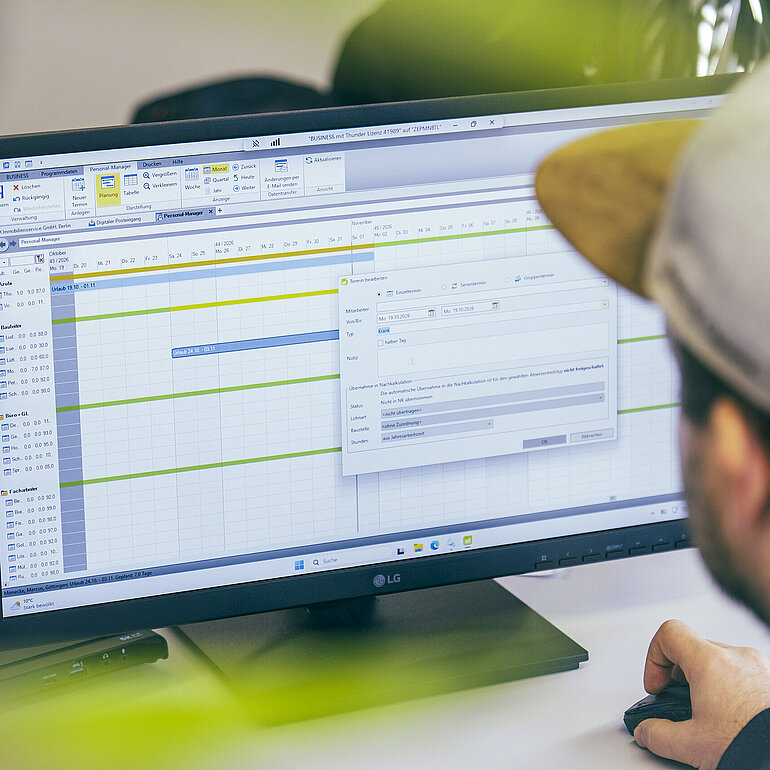 Mitarbeiter arbeitet am Computer mit dem Personal-Manager in BUSINESS zur digitalen Personalplanung und Verwaltung von Abwesenheiten.