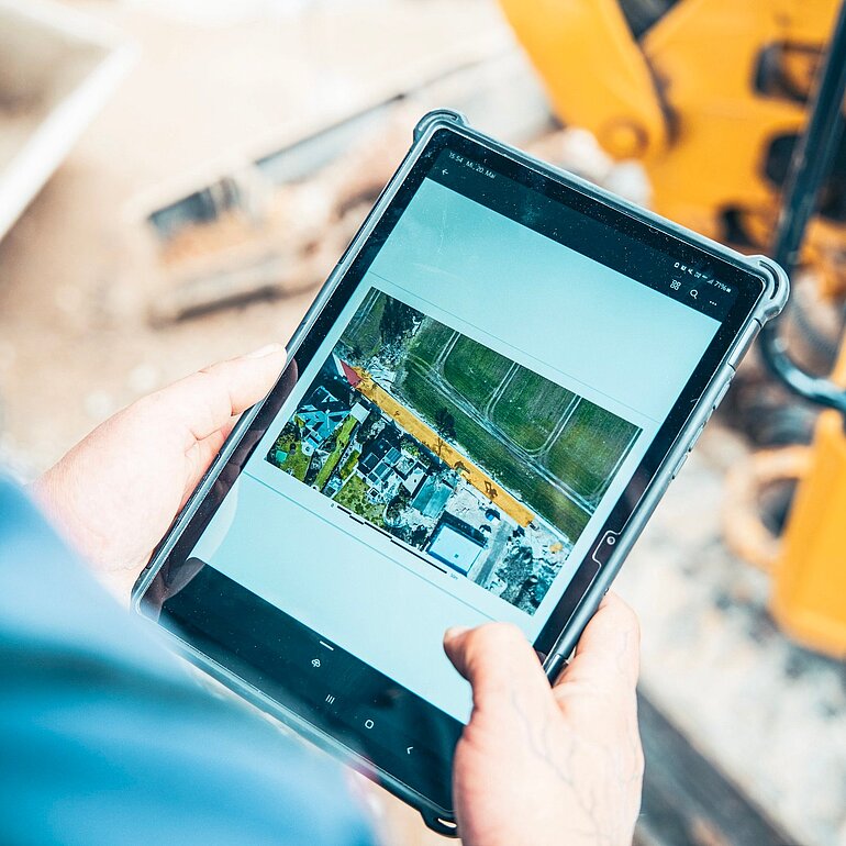 Bauleiter betrachtet Projektdaten auf einem Tablet auf der Baustelle