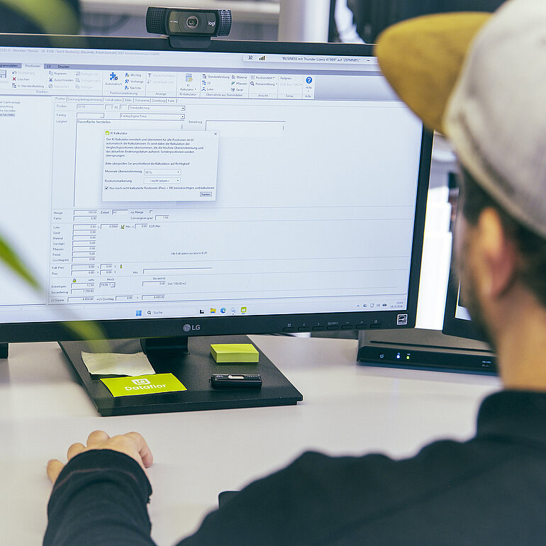 Dataflor Mitarbeiter arbeitet am Computer mit dem KI-Kalkulator in BUSINESS zur KI-gestützten Kalkulation von Leistungsverzeichnissen.